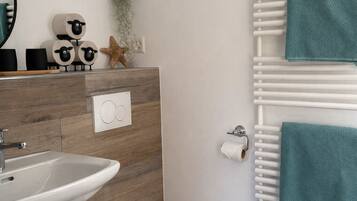 Ein modernes Badezimmer mit einem Holzbadezimmerhocker, einem Waschbecken, einer Toilette und einem Handtuchhalter.
