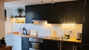A modern kitchen with dark cabinets, a wooden countertop, and a built-in oven.