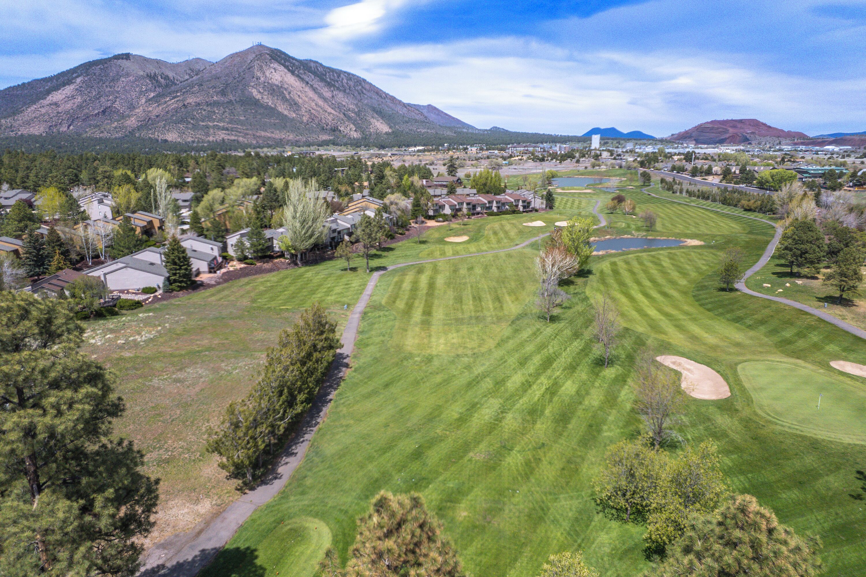 A golf course with a mountain backdrop, residential area, and a clear sky.