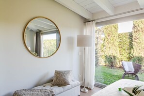 A bedroom with a large window, a round mirror, a floor lamp, a sofa, and a chair. - Farmhouse in Tuscany With Private Pool (Castelfranco di Sotto)