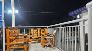 Een balkon met een hekwerk, houten meubels en een betegelde vloer.