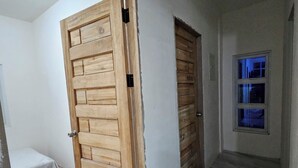 Een gang met een houten deur, een klein bed en een raam met blauwe verlichting.
