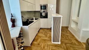 A modern kitchen with white cabinets, a built-in oven, and a herringbone wooden floor. - Luxury Apartment Paris Trocadero- 2 bedrooms 80m2 (Paris)