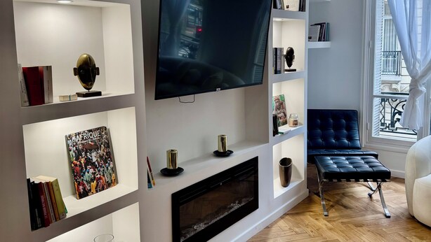 A modern living room with a flat-screen TV, built-in shelves, a fireplace, and a blue sofa. - Luxury Apartment Paris Trocadero- 2 bedrooms 80m2 (Paris)