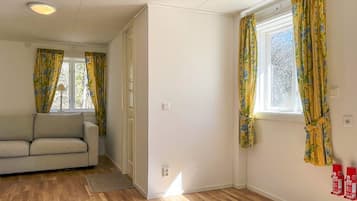 A room with a sofa, a window with curtains, a wooden floor, and a door.