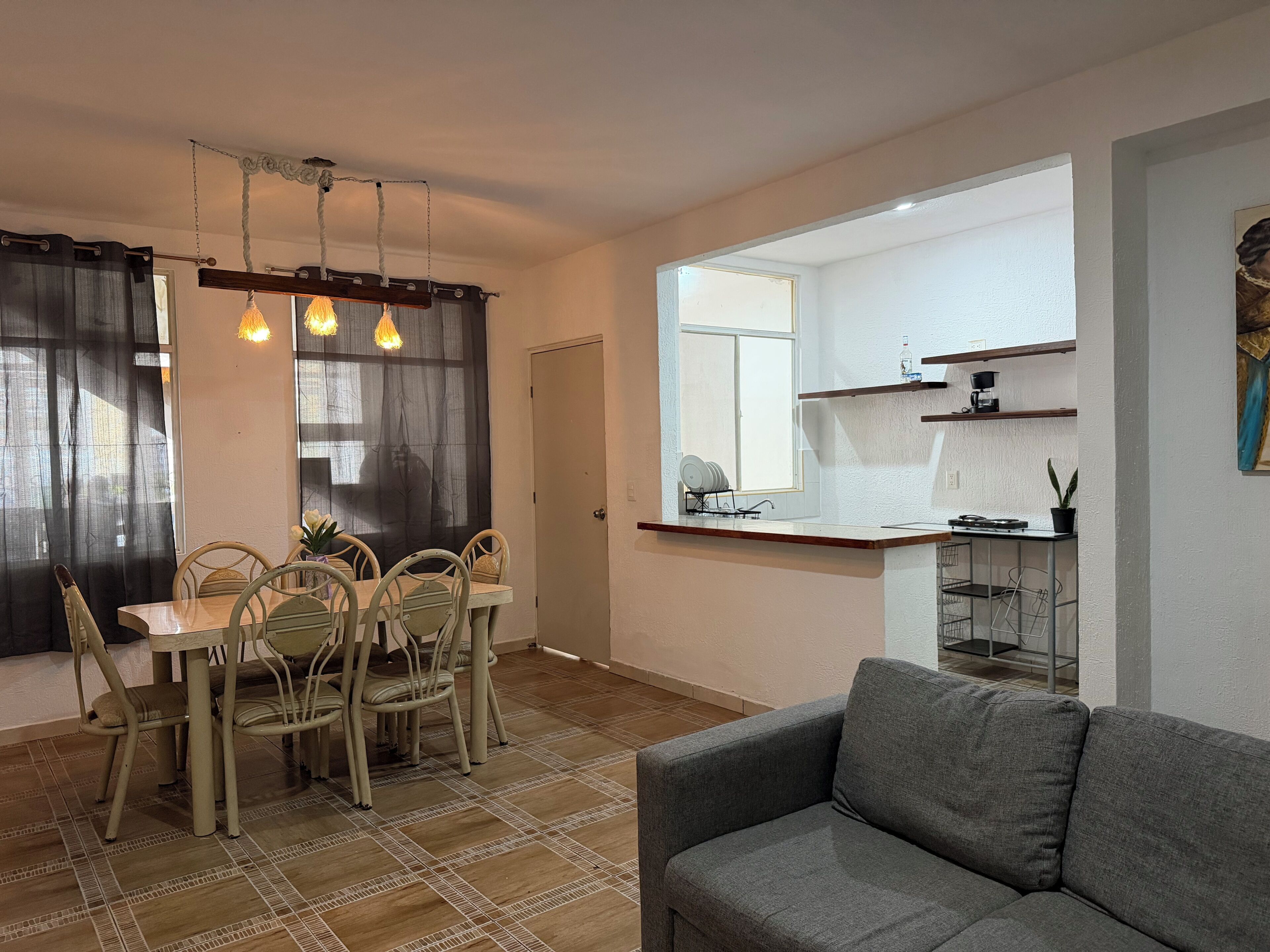 A compact living space with a dining area, kitchenette, and a gray sofa.