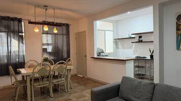 A compact living space with a dining area, kitchenette, and a gray sofa.