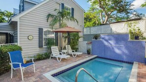 Uma propriedade residencial com piscina, um alpendre coberto com espreguiçadeiras e uma cerca branca.