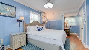 Quarto com cama, mesa de cabeceira, penteadeira e janela.