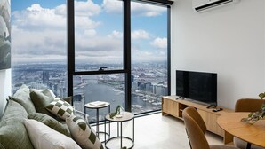 Een moderne woonkamer met een groot raam, een flatscreen televisie, een bank, een salontafel en een eethoek.