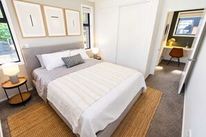 Ein ordentlich eingerichtetes Schlafzimmer mit Bett, Nachttischlampen, Schreibtisch und Stuhl.