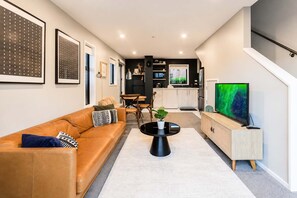 Ein modernes Wohnzimmer mit einer Ledersofa, einem Couchtisch und einem Fernseher auf einer Holzeinrichtung.