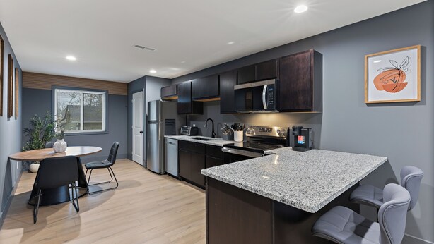 A modern kitchen with dark cabinets, a granite countertop, and stainless steel appliances. - Luxury 2 BD Apartment (Festus)