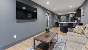A modern living room with a flat-screen TV, a wooden coffee table, and a sofa with patterned cushions. - Luxury 2 BD Apartment (Festus)
