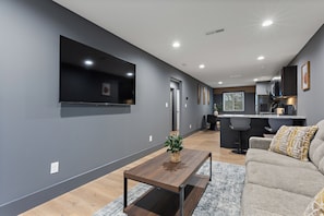 A modern living room with a flat-screen TV, a wooden coffee table, and a sofa with patterned cushions.