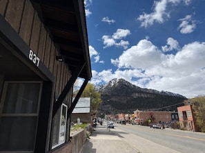 A street view with a mountain in the background, a building with the number 837, and a clear sky. - The Box Canyon Retreat on Main St. with AC! (Ouray)