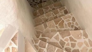 Una estrecha escalera con piso de losas de piedra que lleva a una puerta.