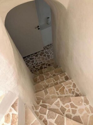 A narrow stairway with a stone-tiled floor leading to a door.