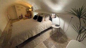 Un dormitorio con cama, una silla, una lámpara y una planta en maceta.