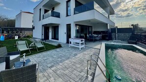 Een modern herenhuis met zwembad, buitenzitplaatsen en een patio.