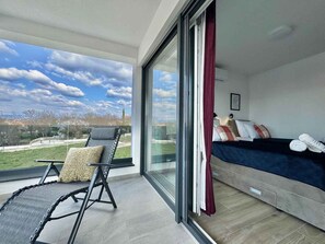 A balcony with a view, a bed with pillows, and a chair. - Villa with swimming pool (Malinska)