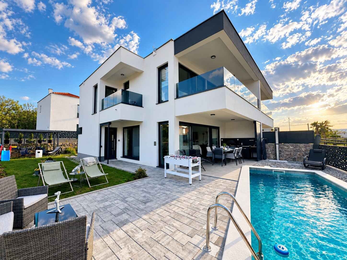 A modern two-story house with a swimming pool, outdoor seating, and a patio area.