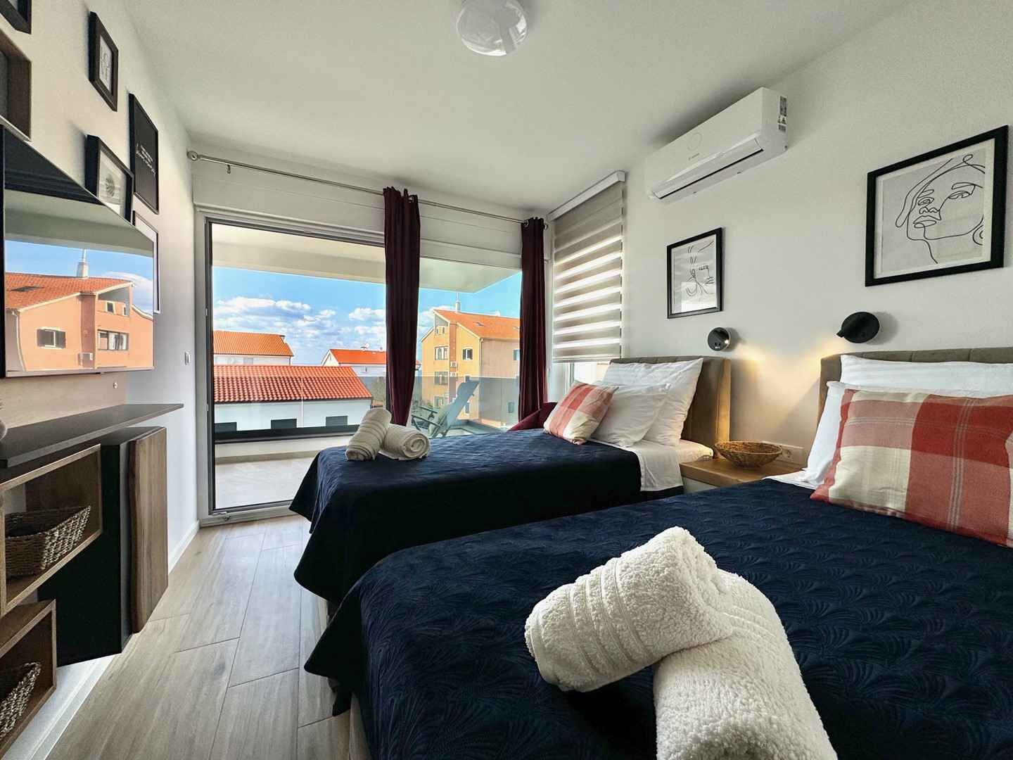 Une chambre d’hôtel avec deux lits, une télévision, une cheminée et un balcon offrant une vue sur la ville.