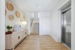A hallway with a wooden floor, a white door, and a staircase in the background. - *New* Canal front home with paddle boards, kayaks! (Anna Maria)
