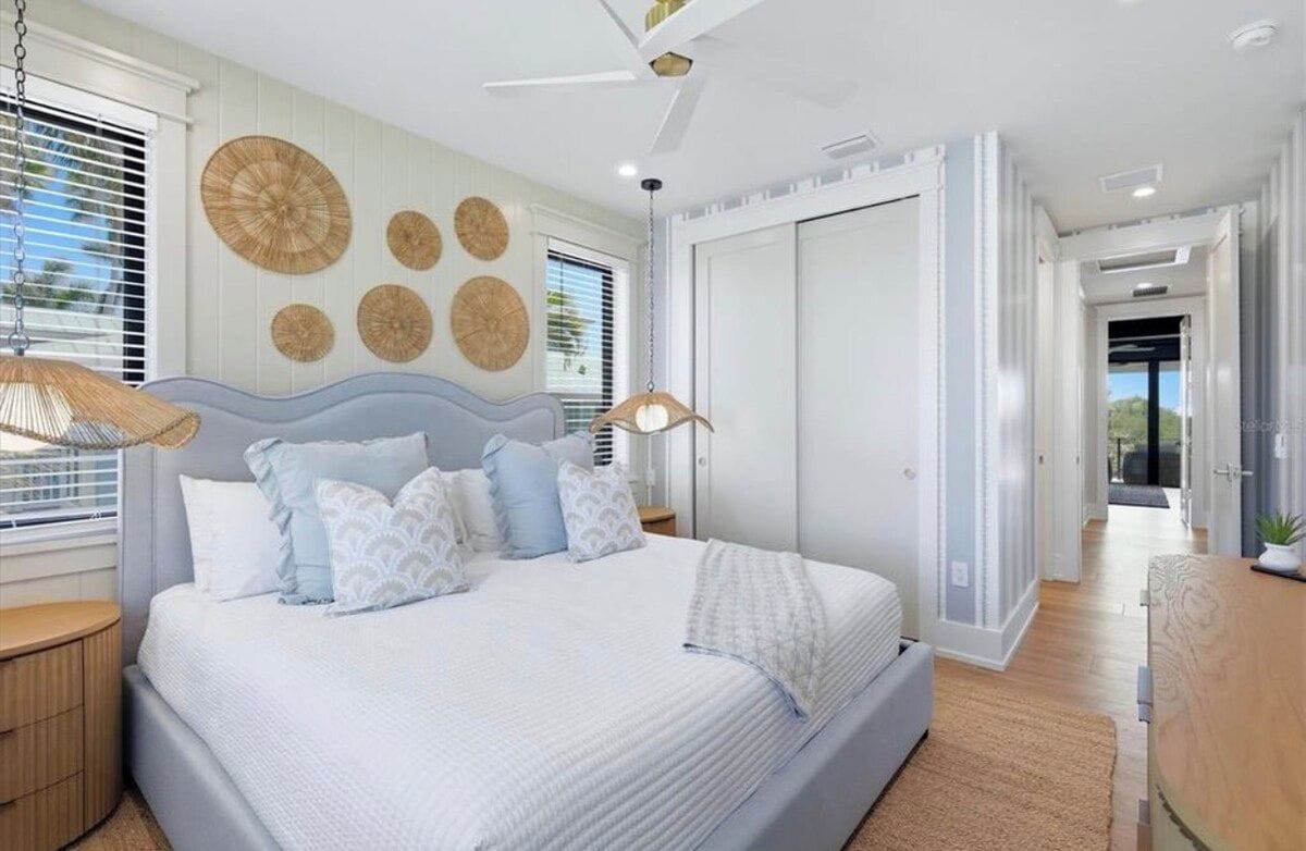A modern bedroom with a large bed, a ceiling fan, and a view of a balcony.