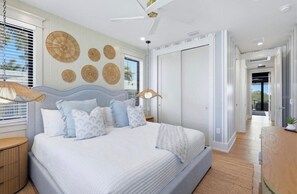 Une chambre moderne avec un grand lit, un ventilateur de plafond et une vue sur un balcon.