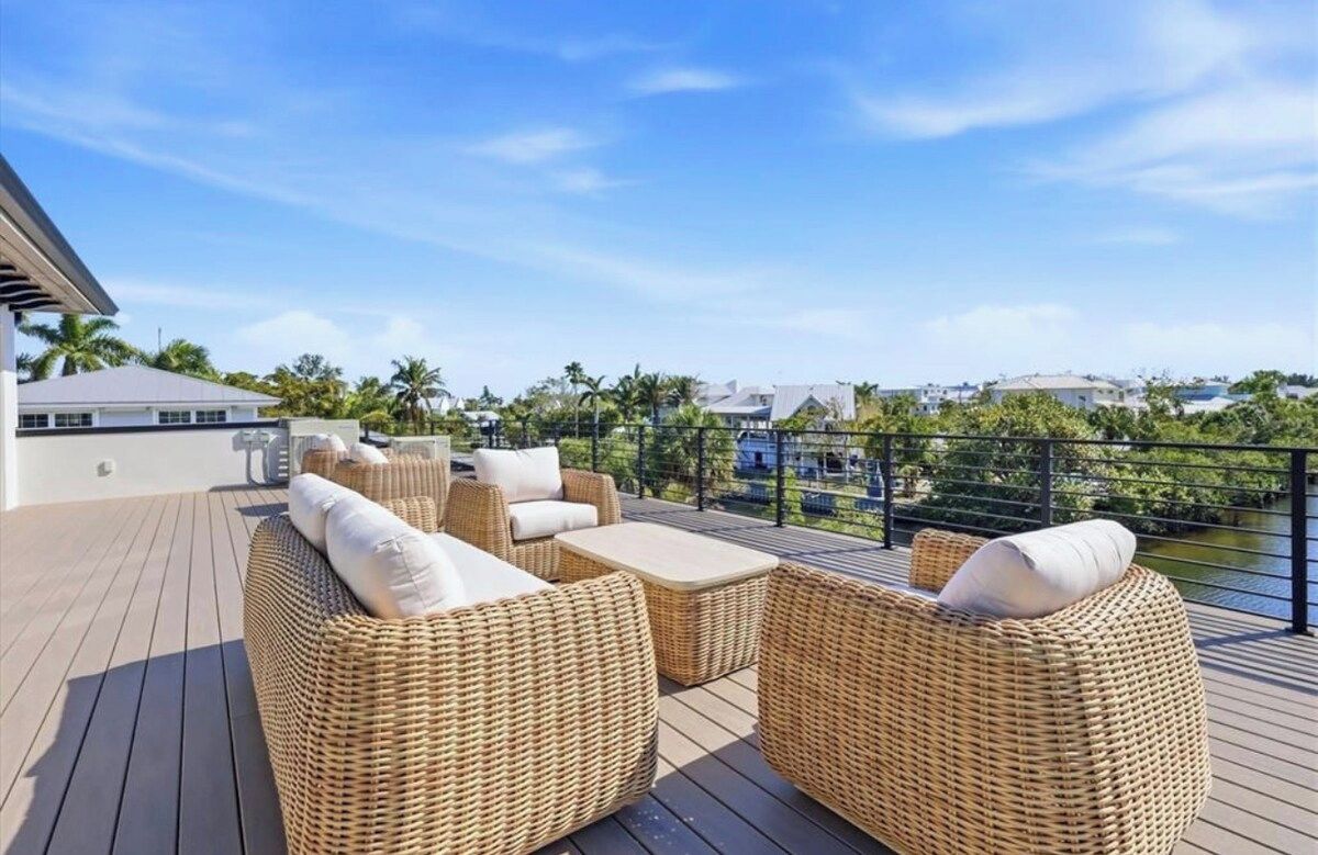 A deck with wicker furniture and a view of a water body.