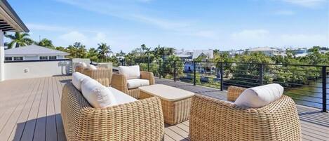 A deck with wicker furniture and a view of a water body.
