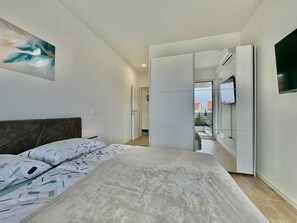 Um quarto moderno com uma cama, um quadro, um guarda-roupa e uma televisão.