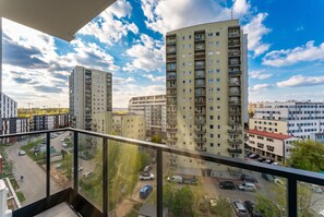 A high-rise residential building with multiple balconies and a view of a parking area. - Tauron Arena Chic Apartment (Kraków)