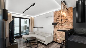 Ein modernes Wohnzimmer mit einem Ecksofa, einem runden Couchtisch, einem Fernseher und einer Wand mit Backsteinverkleidung.