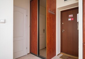 L’entrée d’une chambre d’hôtel se compose d’une porte coulissante, d’une porte en bois avec une pancarte et d’un paillasson.