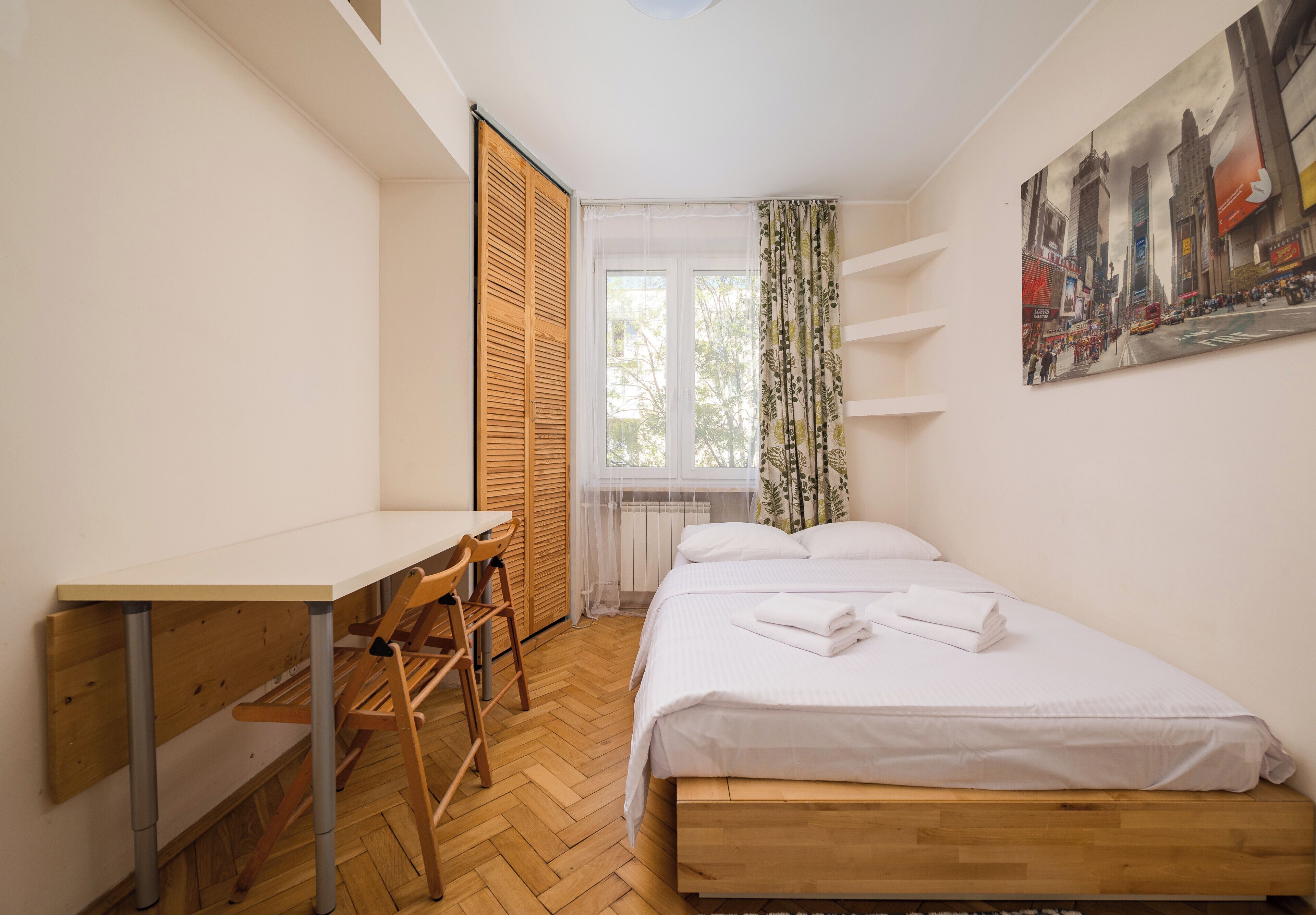 A bedroom with a bed, a desk, and a chair.