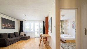 Ein modernes Wohnzimmer mit einer Couch, einem Esstisch und einem angrenzenden Schlafzimmer.
