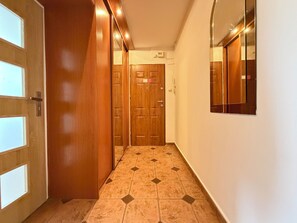 Ein Korridor mit Holztüren, Fliesenboden und einem Spiegel an der Wand.