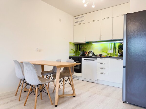 A modern kitchen with white cabinets, a wooden dining table, and grey chairs.