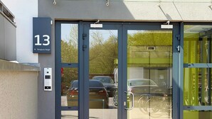 A building entrance with a glass door, a keypad, and a sign with the number 13.