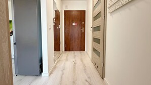 A hallway with a refrigerator, wooden doors, and a wall-mounted pegboard.