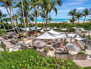 Ein Strandhotel mit Außenbereich, Palmen und Meerblick.