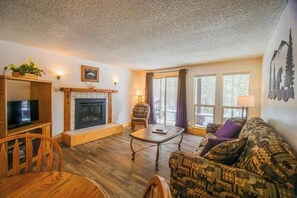 A cozy living room with a fireplace, a television, a sofa, and a dining table.