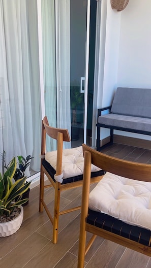 Una silla de madera con cojín, un sofá y una planta en maceta.