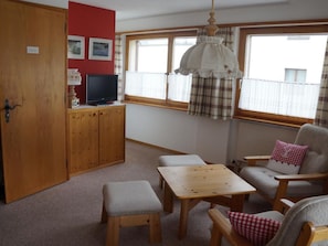 A cozy room with a wooden cabinet, a television, a table, and a chair. - Chesa Chastelets by Interhome (Sils Maria)