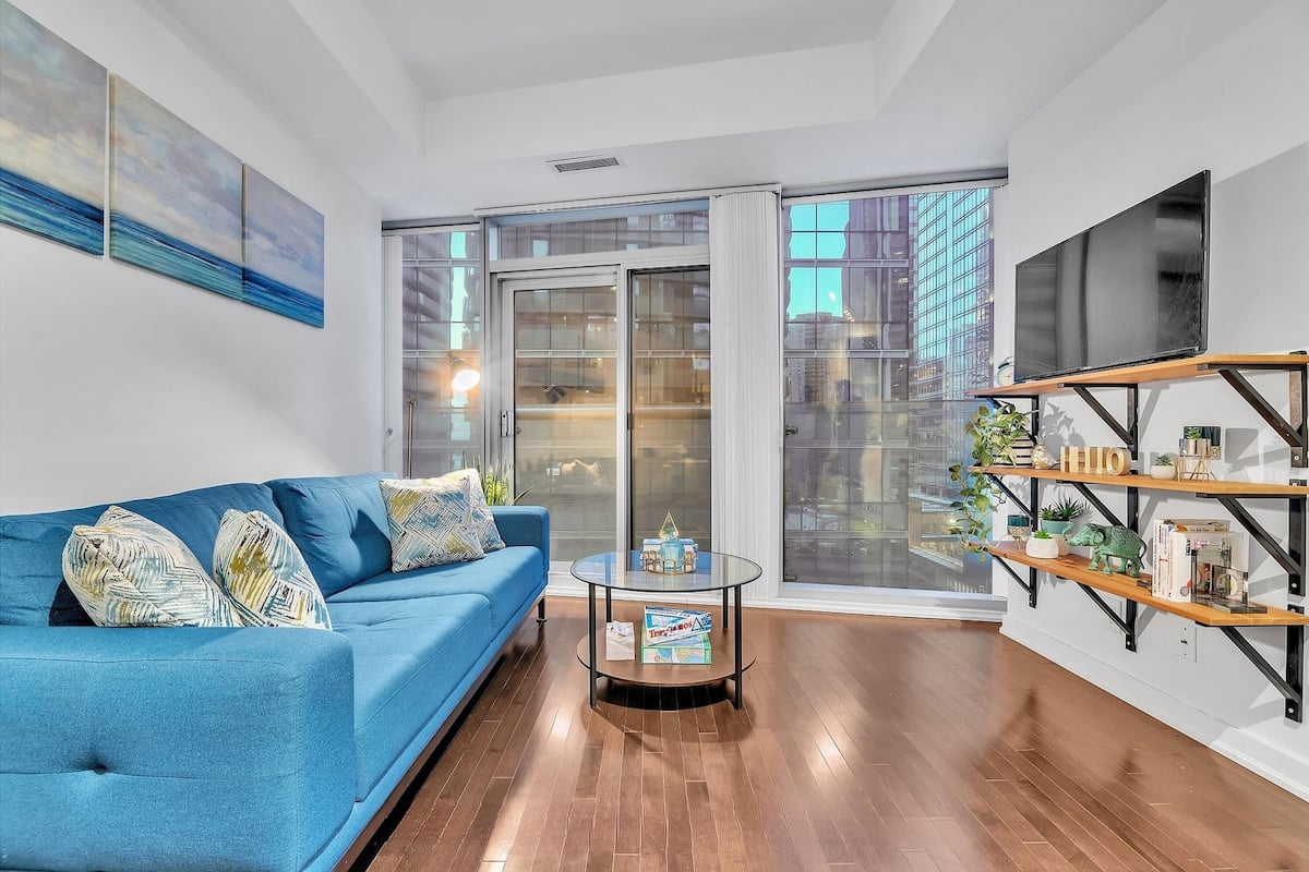 Una sala de estar moderna con un sofá azul, una mesa de centro de vidrio y una estantería.