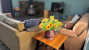 A living room with a sofa, a coffee table with a vase of sunflowers, a fireplace, and a television.