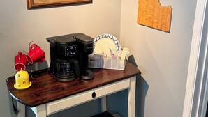 A coffee station with a Keurig machine, red cups, and a yellow lamp.