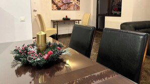 Un coin repas avec une table en bois, des chaises en cuir noir, un élément décoratif au centre de la table et un tableau au mur.